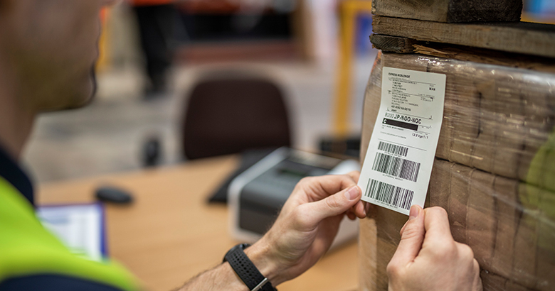 Tvornički radnik lijepi naljepnicu na paket ispisanu tehnologijom izravnog termalnog ispisa​