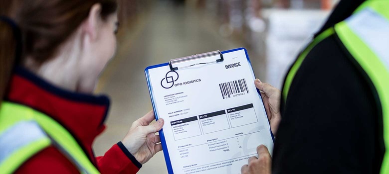 Muškarac i žena u signalnim prslucima u skladištu drže mapu s računima