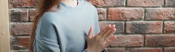 Žena sjedi i drži sklopljene dlanove 