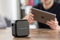 Muškarac s tabletom i P-touch Cube Plus koji ima bateriju